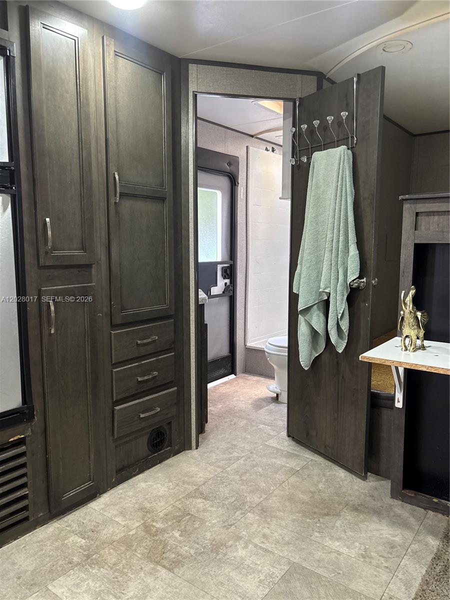 A view of a camper interior featuring dark wood cabinetry, a bathroom, and tiled flooring — 14165 NW 22nd Ct # A, Opa-Locka FL 33054, OPA-LOCKA, FL
