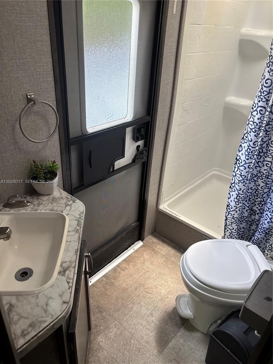 A small bathroom in a recreational vehicle features a sink, toilet, and shower stall — 14165 NW 22nd Ct # A, Opa-Locka FL 33054, OPA-LOCKA, FL