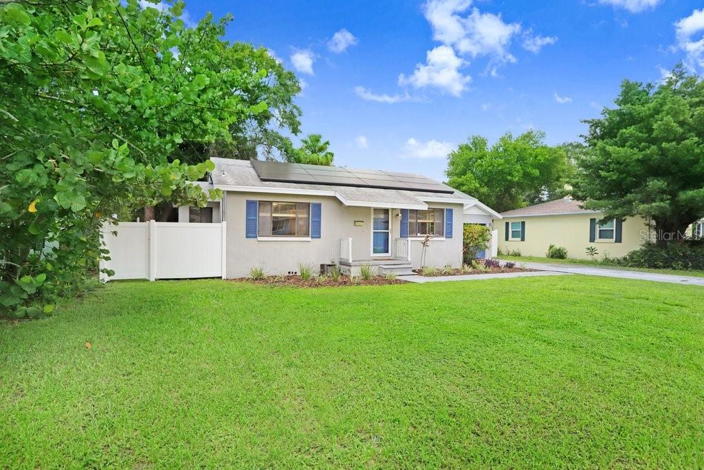 A single-story house with solar panels on the roof and a white privacy fence — 4415 W BAY VILLA AVENUE, TAMPA, FL