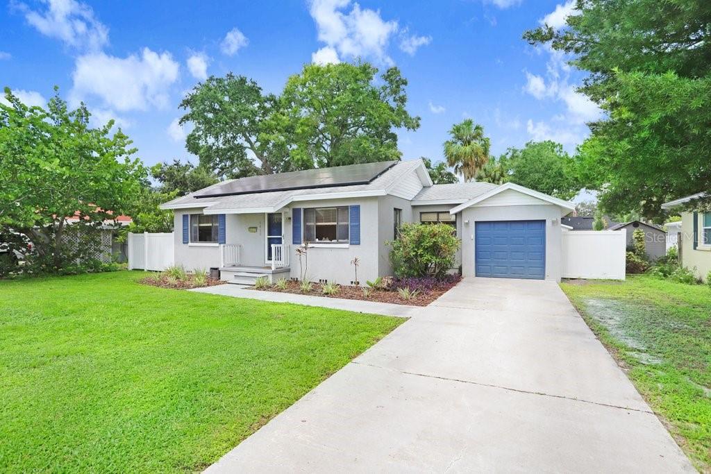 A single-story house with a gray exterior, blue shutters, a garage, and rooftop solar panels — 4415 W BAY VILLA AVENUE, TAMPA, FL