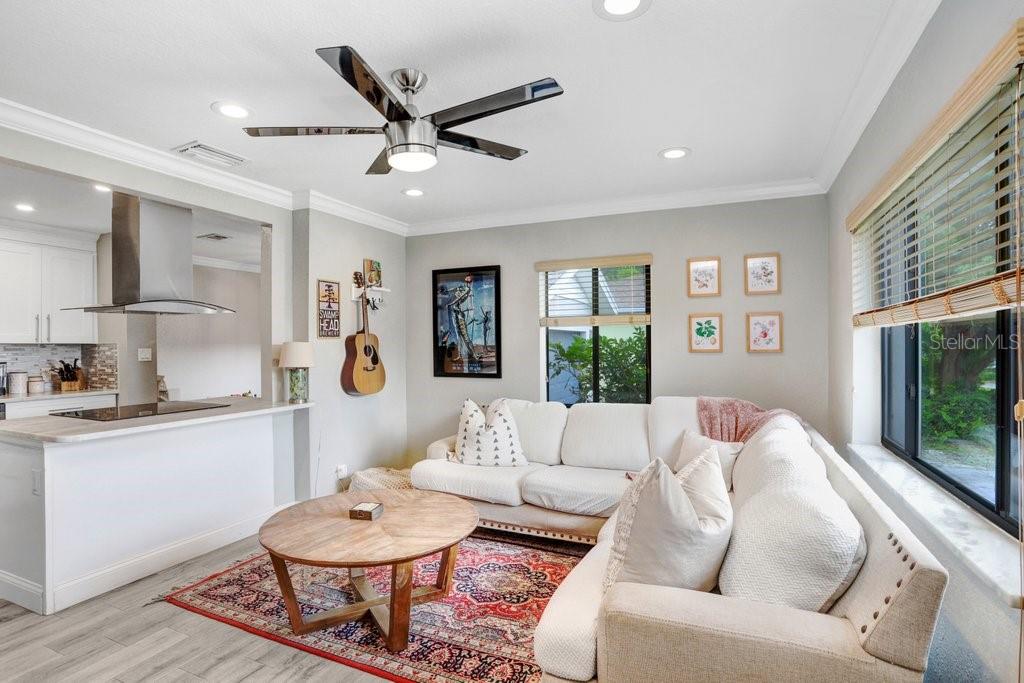 A living room with a white sectional sofa, round wooden coffee table, and patterned rug — 4415 W BAY VILLA AVENUE, TAMPA, FL