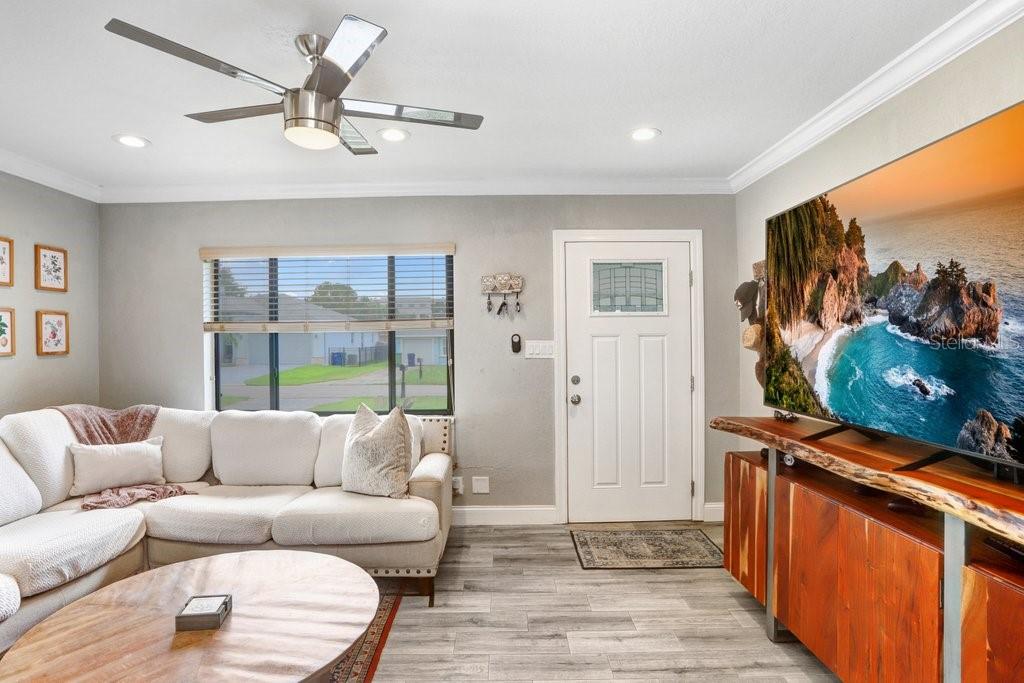 A living room features a white sectional sofa, wood-topped media console, and a ceiling fan — 4415 W BAY VILLA AVENUE, TAMPA, FL