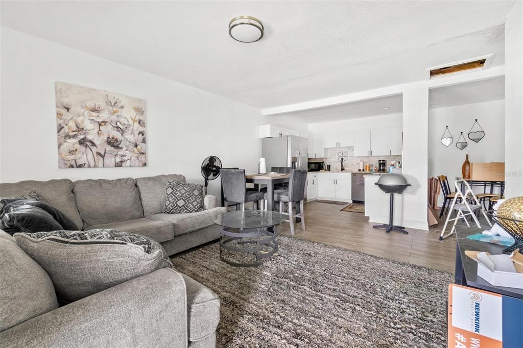 A living room with a gray sofa and rug opens into a white kitchen area — 6426 S HIMES AVENUE, TAMPA, FL