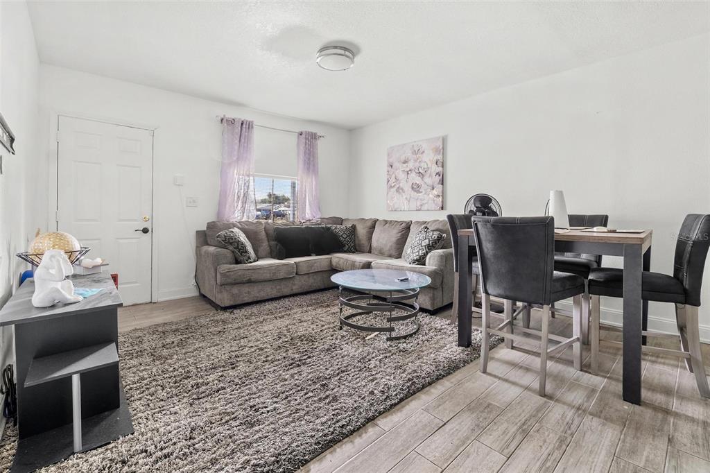 A living room features a gray sectional sofa, a dining set, and a large area rug — 6426 S HIMES AVENUE, TAMPA, FL