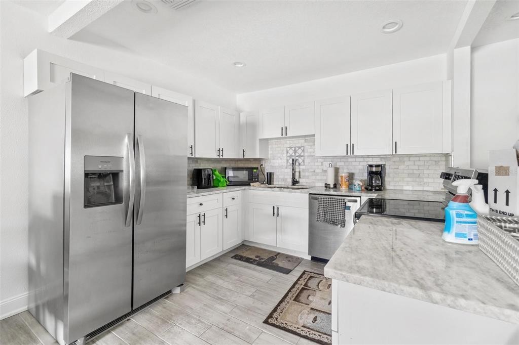 A kitchen features white cabinets, stainless steel appliances, and marble-look countertops — 6426 S HIMES AVENUE, TAMPA, FL
