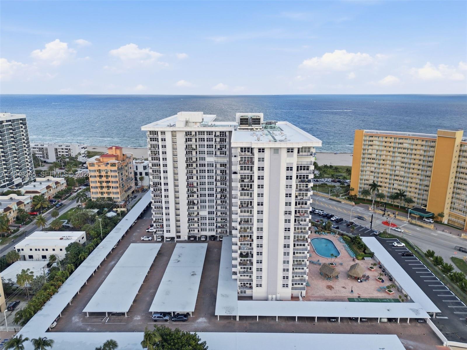 An aerial view shows a high-rise apartment building with a pool and covered parking — 405 N Ocean Blvd # 1528, Pompano Beach FL 33062, POMPANO BEACH, FL