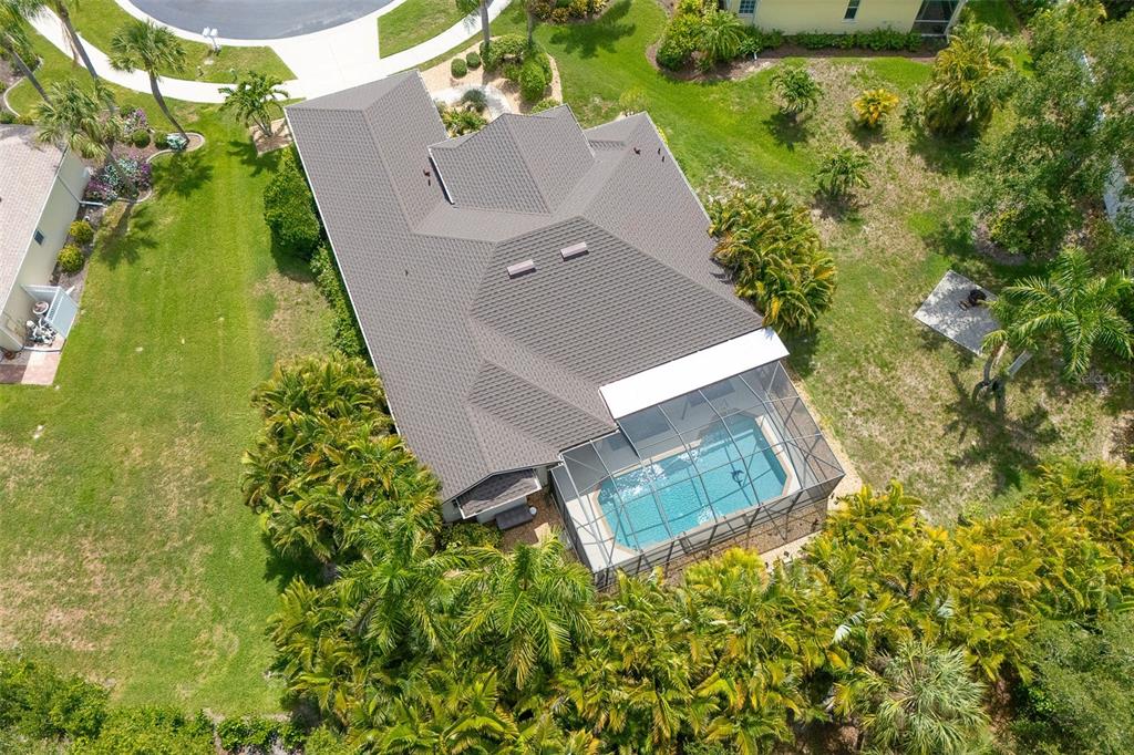 An aerial view shows a house with a dark shingled roof and a screened-in pool — 122 CLEAR LAKE DRIVE, ENGLEWOOD, FL