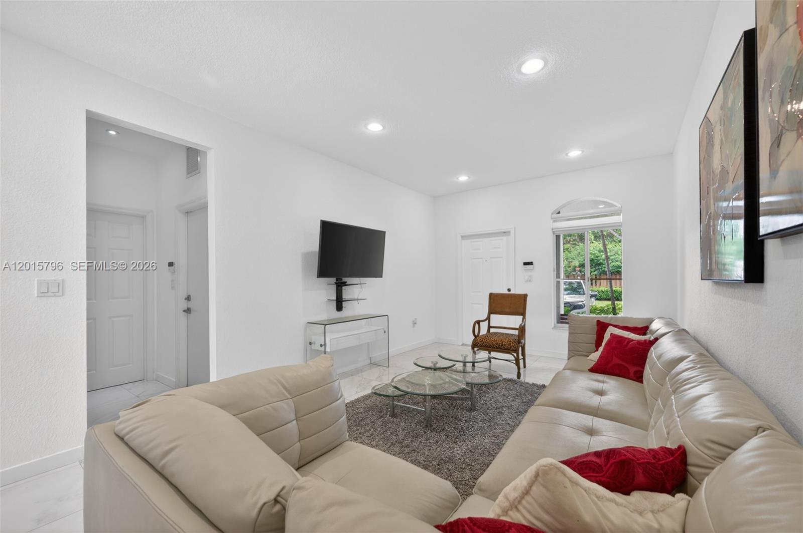 A living room features a beige sectional sofa, glass coffee tables, and a wall-mounted television — 11248 NW 56th St, Doral FL 33178, DORAL, FL