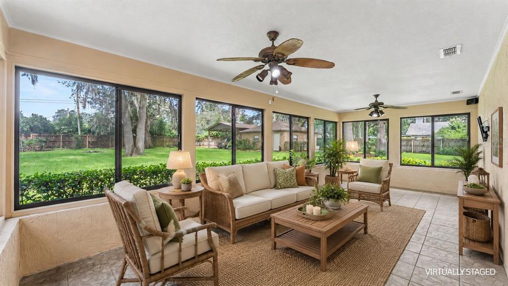 A sunroom features tile floors, wicker furniture, and large windows overlooking a grassy backyard — 6625 FORESTWOOD DRIVE W, LAKELAND, FL