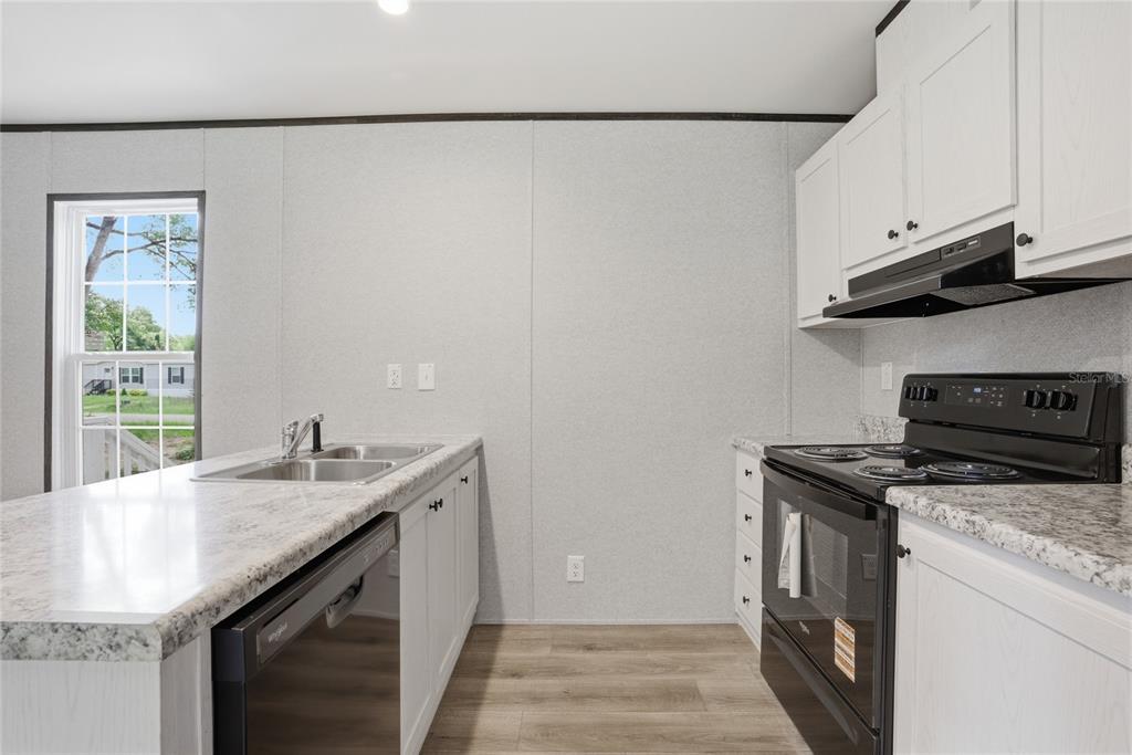 A kitchen features white cabinets, a black stove, a dishwasher, and a light-colored countertop — 11311 NW 13TH STREET, OCALA, FL