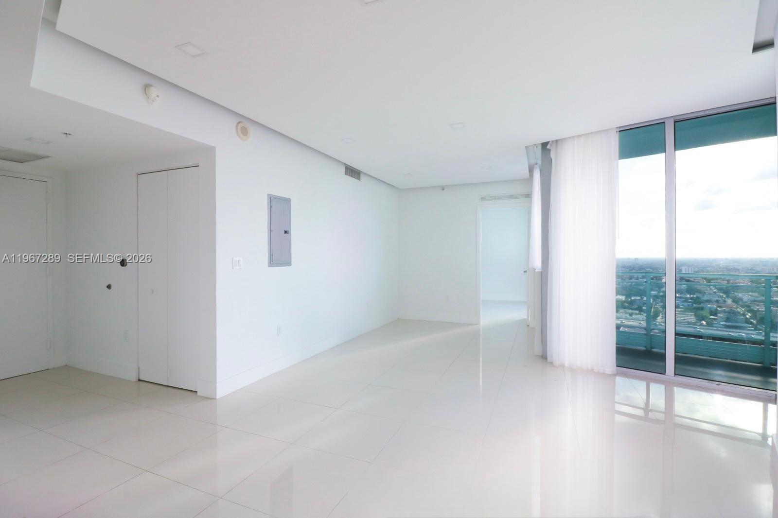 An empty, white-walled room features glossy tile floors, a closet, and a balcony view — 92 SW 3rd St # 2706, Miami FL 33130, MIAMI, FL