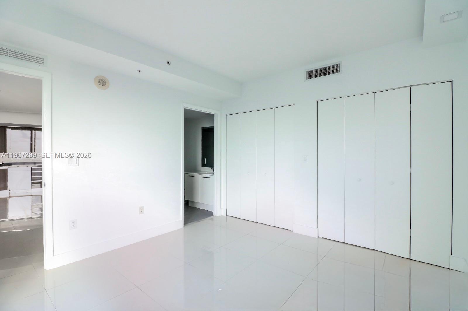 A minimalist room features white tile flooring, white walls, and two sets of closet doors — 92 SW 3rd St # 2706, Miami FL 33130, MIAMI, FL