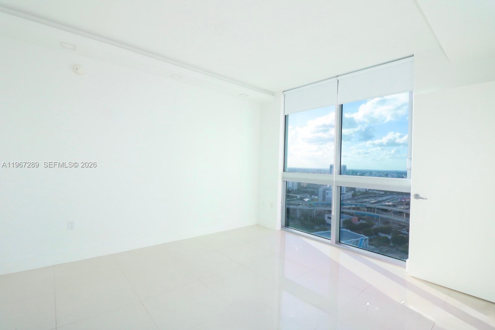 An empty room with white walls, tile flooring, and floor-to-ceiling windows overlooking a city — 92 SW 3rd St # 2706, Miami FL 33130, MIAMI, FL