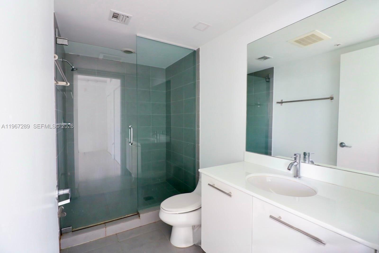A modern bathroom features a glass-enclosed shower, a white vanity, and a large wall mirror — 92 SW 3rd St # 2706, Miami FL 33130, MIAMI, FL