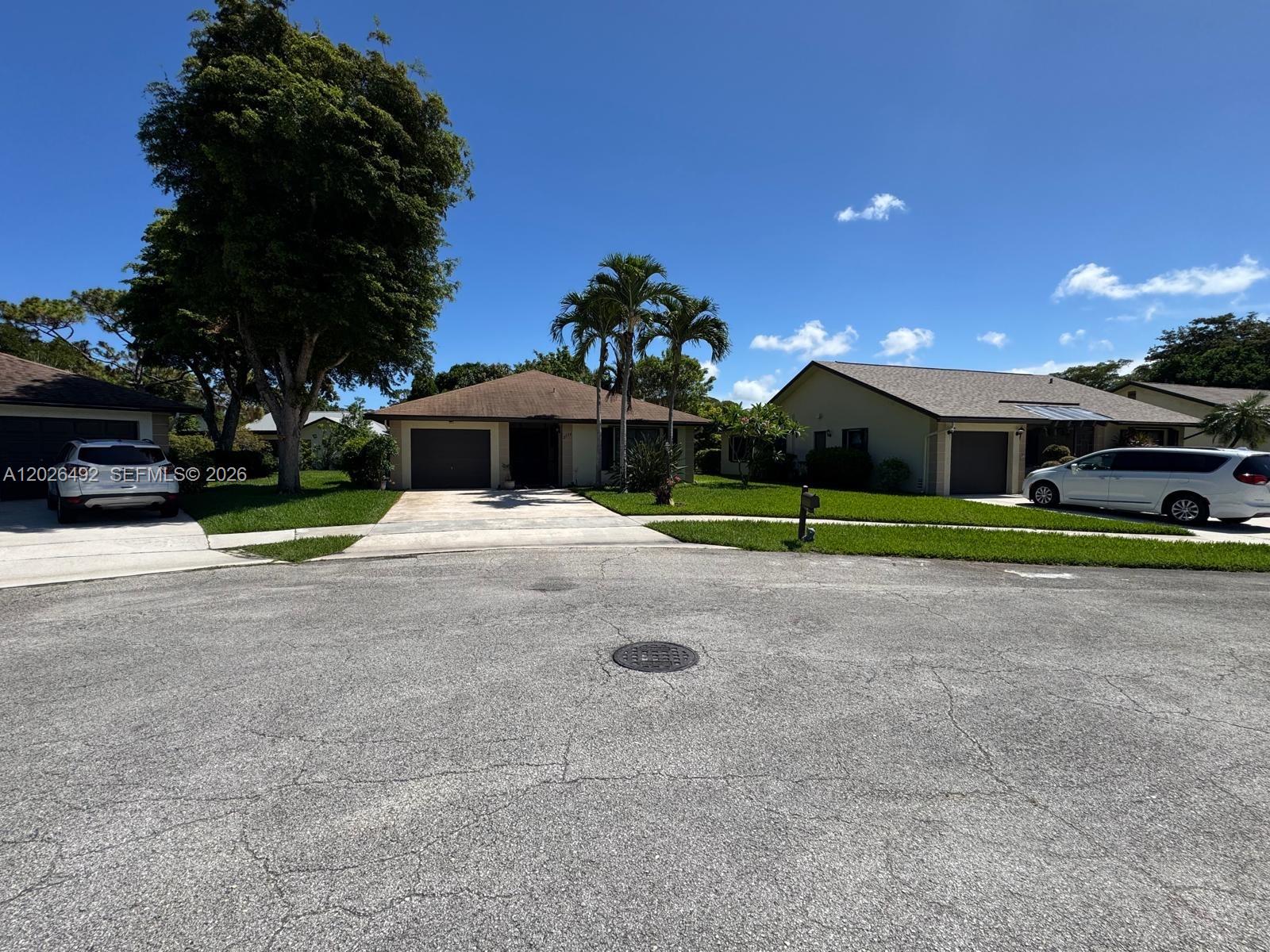 A street view of three single-story suburban houses with driveways and lawns under a blue sky — 2736 Carnation Ct # 0, Delray Beach FL 33445, DELRAY BEACH, FL