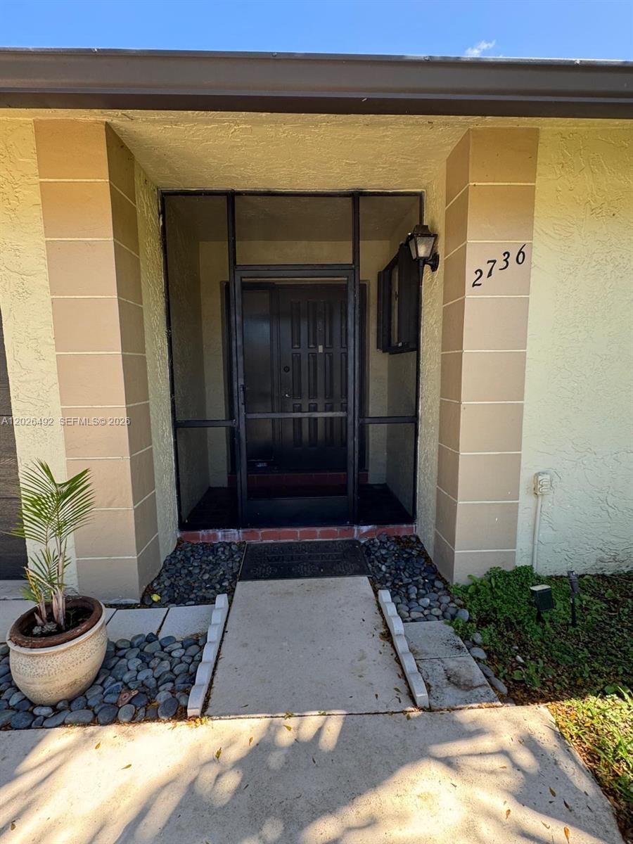 The front entrance features a screened-in porch, a concrete walkway, and a potted palm plant — 2736 Carnation Ct # 0, Delray Beach FL 33445, DELRAY BEACH, FL