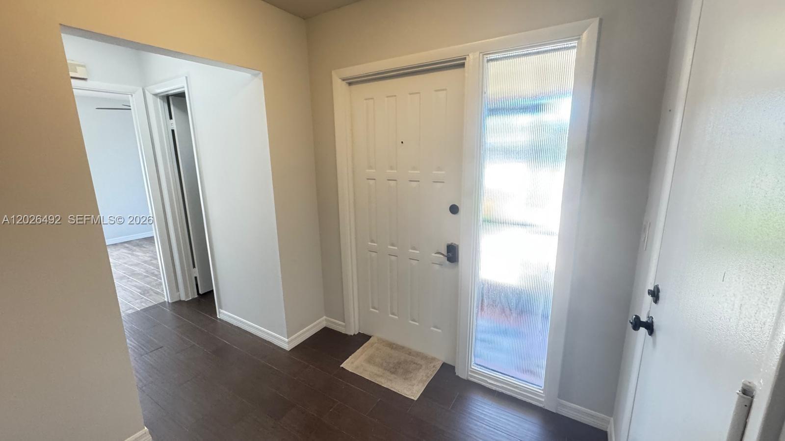 An entryway features a white front door with a fluted glass sidelight and dark flooring — 2736 Carnation Ct # 0, Delray Beach FL 33445, DELRAY BEACH, FL