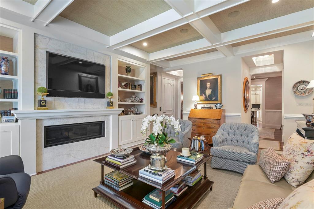 A living room features a fireplace with a mounted television, coffered ceilings, and built-in shelving — 413 W MORSE BOULEVARD, WINTER PARK, FL