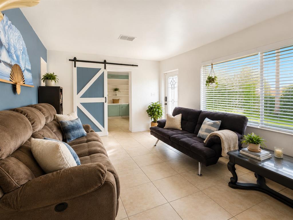 A living room features two sofas, a sliding barn door, and tile flooring — 105 MARGARET STREET, AUBURNDALE, FL