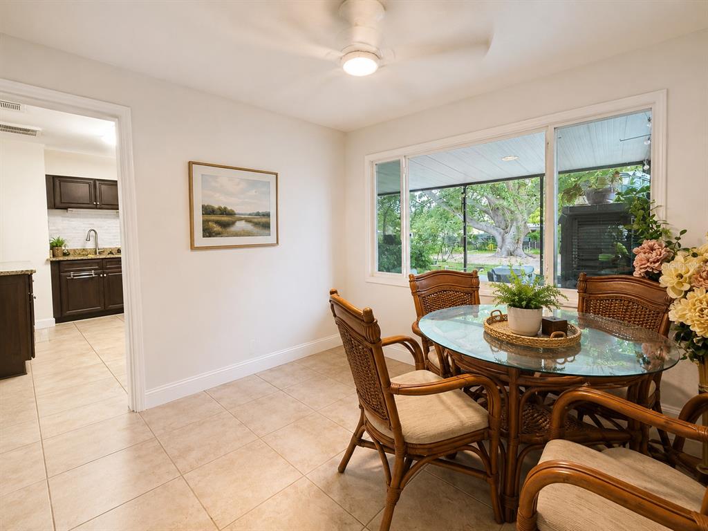 A dining area with a glass-topped rattan table, tile flooring, and a view of a patio — 105 MARGARET STREET, AUBURNDALE, FL