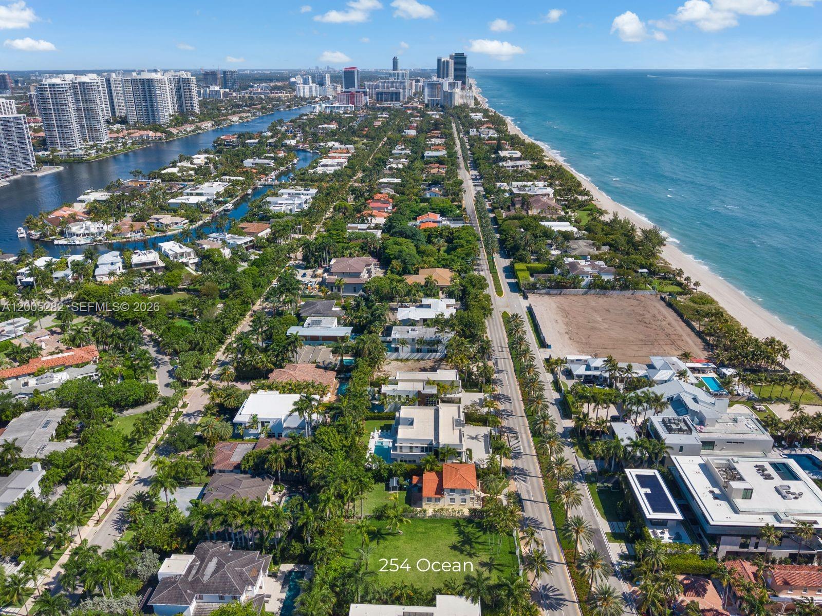 An aerial view shows a coastal neighborhood with houses, palm trees, and a sandy beach — 254 Ocean Blvd, Golden Beach FL 33160, GOLDEN BEACH, FL