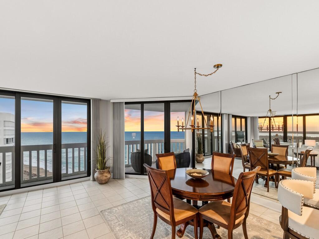 A tall white residential building stands behind a gated entrance with palm trees and flags — 9960 S Ocean Drive # 1905, Jensen Beach FL 34957, JENSEN BEACH, FL