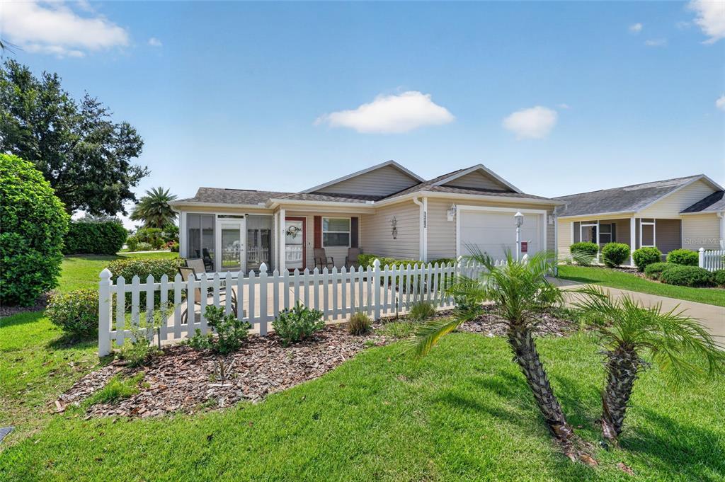 A single-story house with beige siding, a white picket fence, and a screened-in front porch — 1362 VIOLA COURT, THE VILLAGES, FL