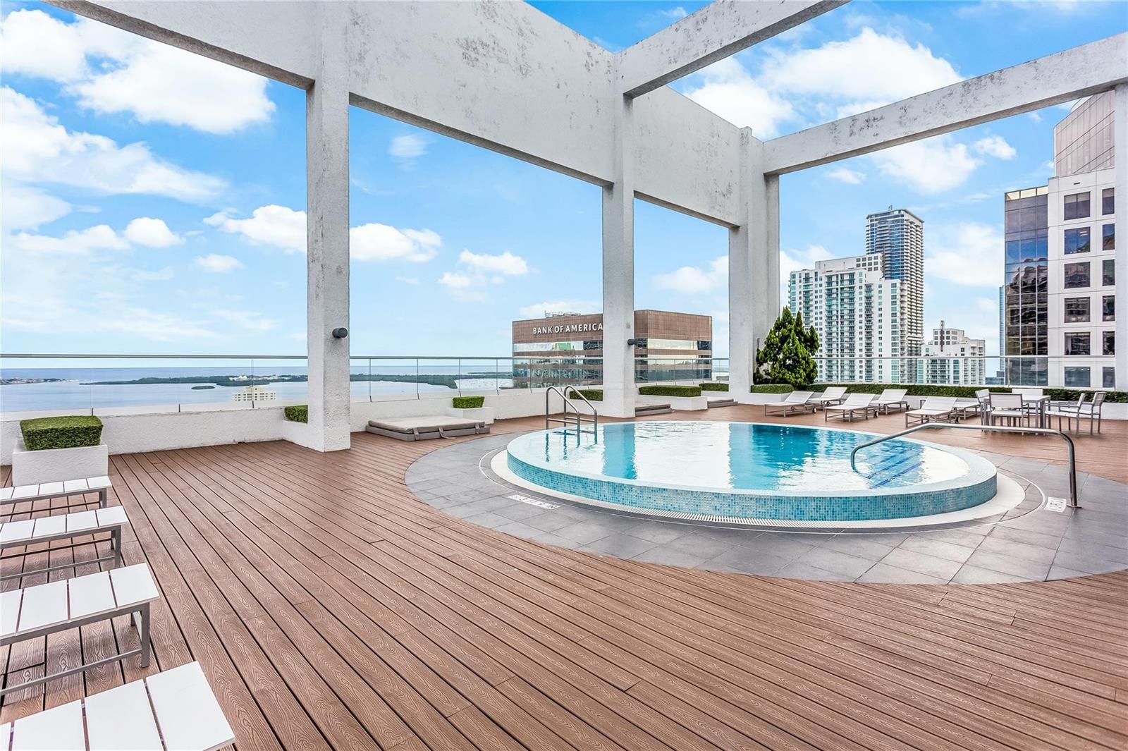 A rooftop pool deck features a circular pool, wooden decking, and views of city buildings — 55 SE 6th Street # 3500, Miami FL 33131, MIAMI, FL