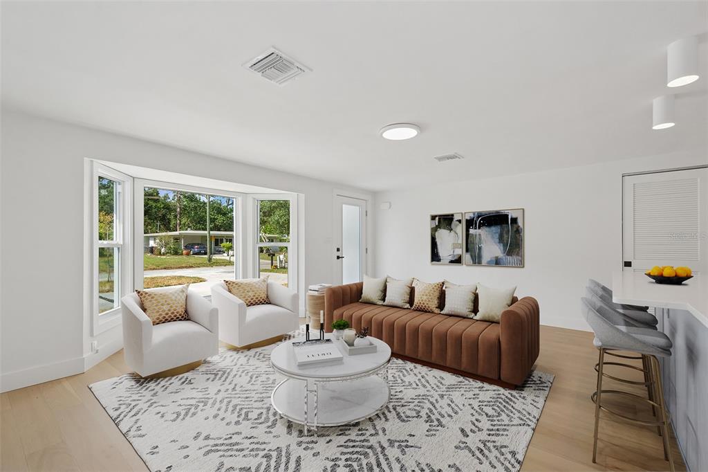A living room features a brown sofa, two white armchairs, and a large bay window — 2655 BAY STREET, SARASOTA, FL