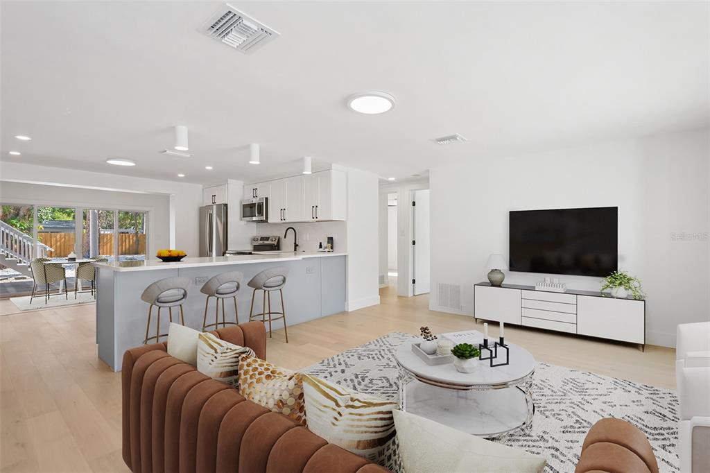 A modern open-concept living room and kitchen featuring light wood floors and white cabinetry — 2655 BAY STREET, SARASOTA, FL
