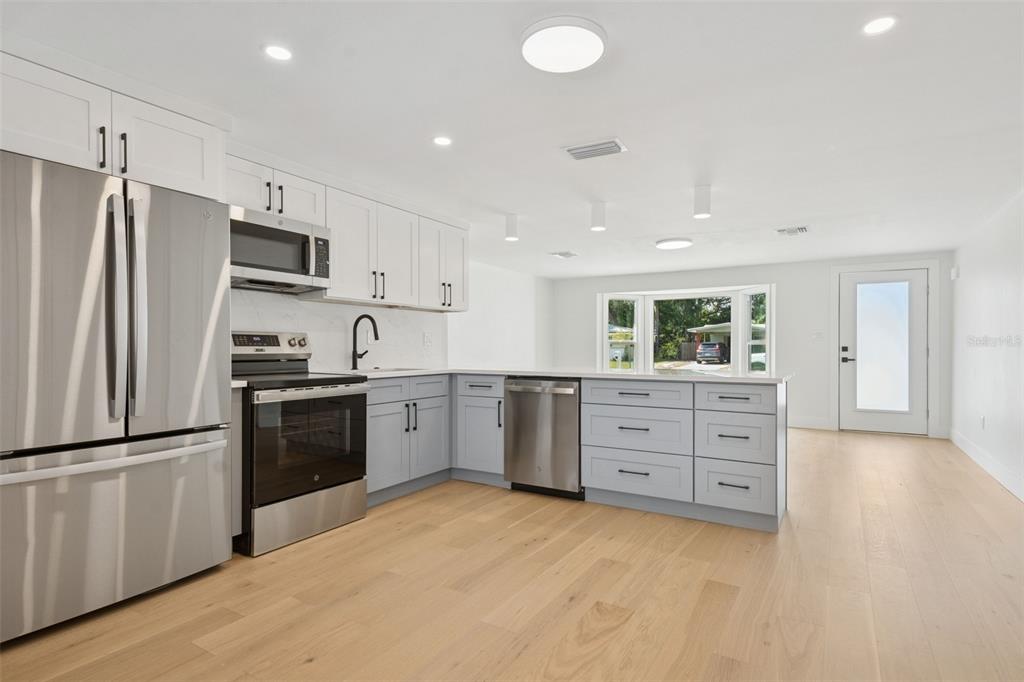 A modern kitchen features white upper cabinets, light blue lower cabinets, and stainless steel appliances — 2655 BAY STREET, SARASOTA, FL