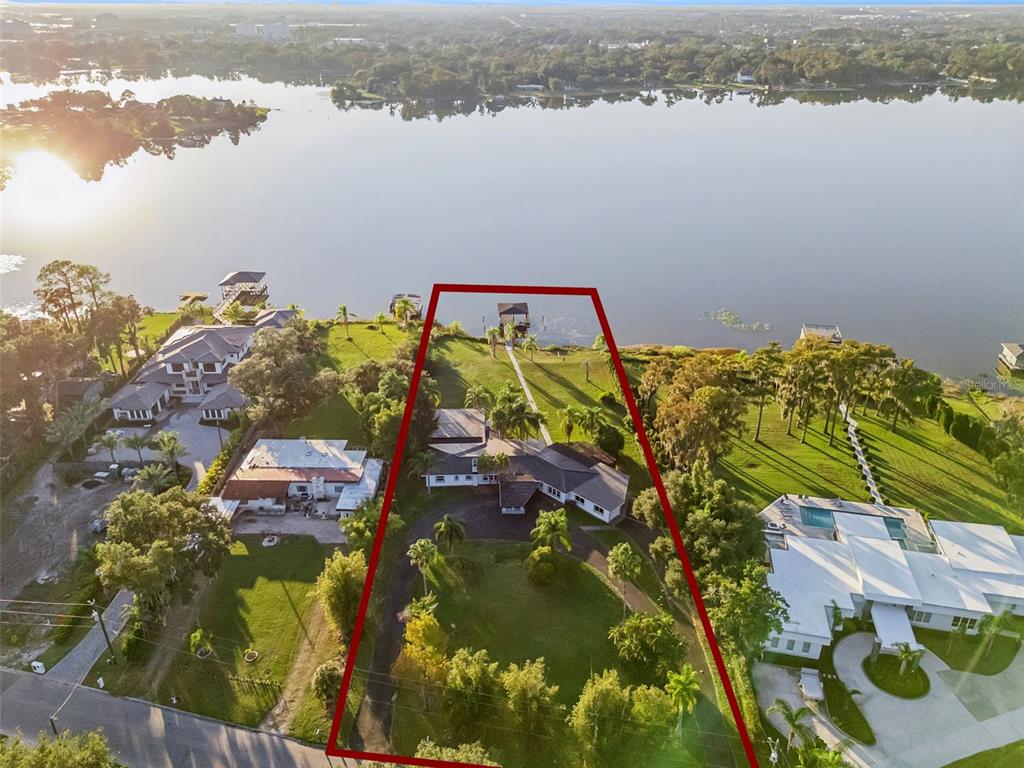 An aerial view shows a waterfront house with a large lawn and private boat dock — 5526 PARKDALE DRIVE, ORLANDO, FL