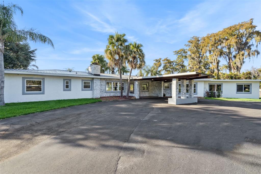A single-story house with a stone-accented facade, a large carport, and a paved driveway — 5526 PARKDALE DRIVE, ORLANDO, FL