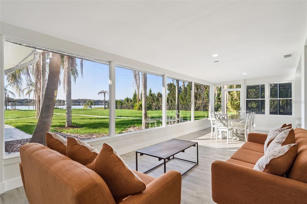 A sunroom with orange sofas, a coffee table, and large windows overlooking a grassy yard — 5526 PARKDALE DRIVE, ORLANDO, FL