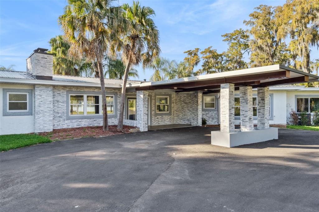 A single-story house with a stone facade and a large covered carport entrance — 5526 PARKDALE DRIVE, ORLANDO, FL