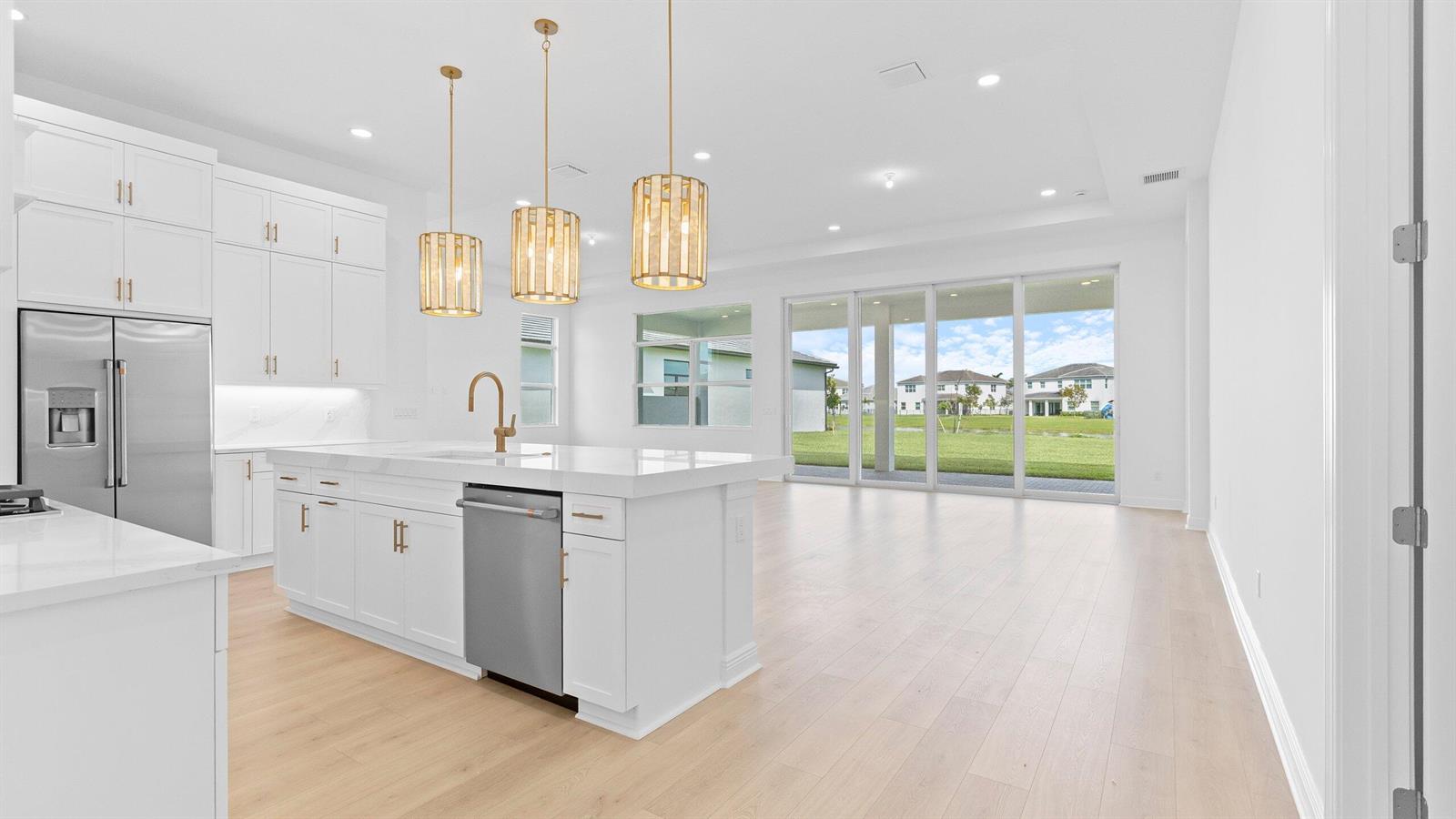 A modern white kitchen with a large island and stainless steel appliances overlooks a backyard — 5468 Hutchinson Way, Westlake FL 33470, WESTLAKE, FL