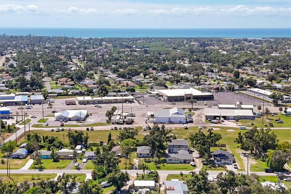 An aerial view shows a suburban neighborhood with commercial buildings and the ocean beyond — 2210,2212,2214 PARK ROAD, VENICE, FL