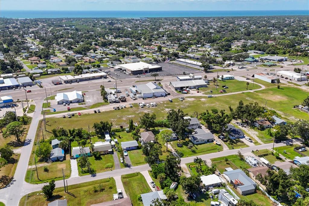 An aerial view shows a commercial area with buildings, parking lots, and surrounding residential properties — 2210,2212,2214 PARK ROAD, VENICE, FL