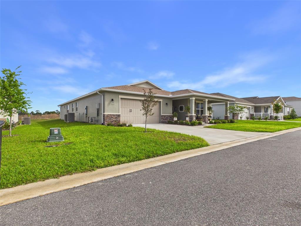 A single-story house with a tan stucco exterior, stone accents, and a two-car garage — 7545 SW 56TH PLACE, OCALA, FL