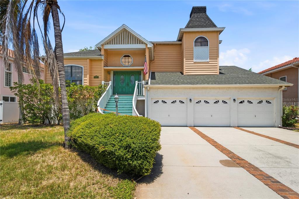 A two-story house with a three-car garage, light-colored siding, and a raised front entrance — 1136 3RD AVENUE S, TIERRA VERDE, FL