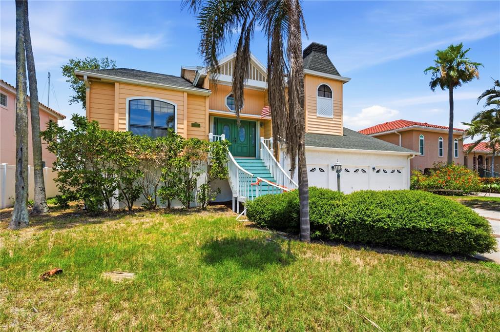 A two-story house with peach siding, a raised entryway, and a three-car garage — 1136 3RD AVENUE S, TIERRA VERDE, FL
