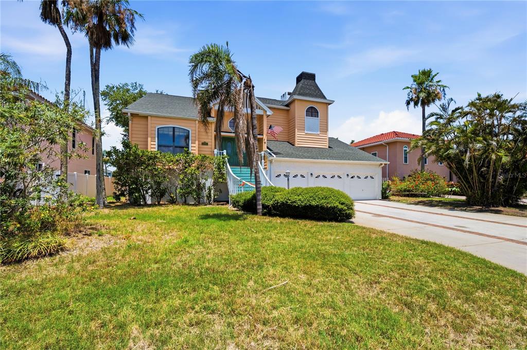 A two-story yellow house with a three-car garage and palm trees in the front yard — 1136 3RD AVENUE S, TIERRA VERDE, FL
