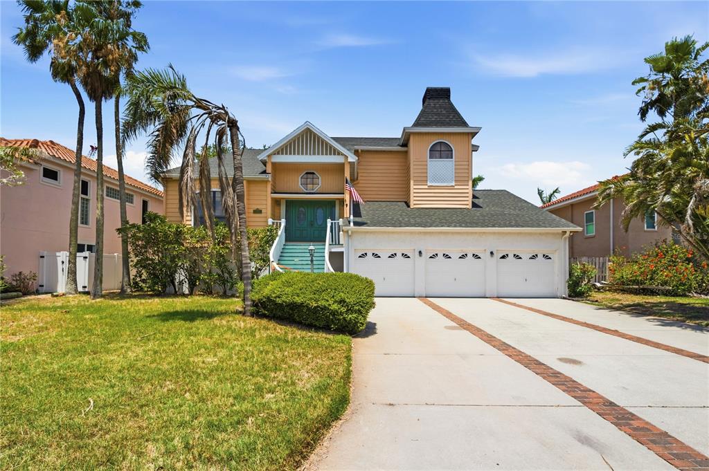 A two-story house with a three-car garage, yellow siding, and a front staircase — 1136 3RD AVENUE S, TIERRA VERDE, FL