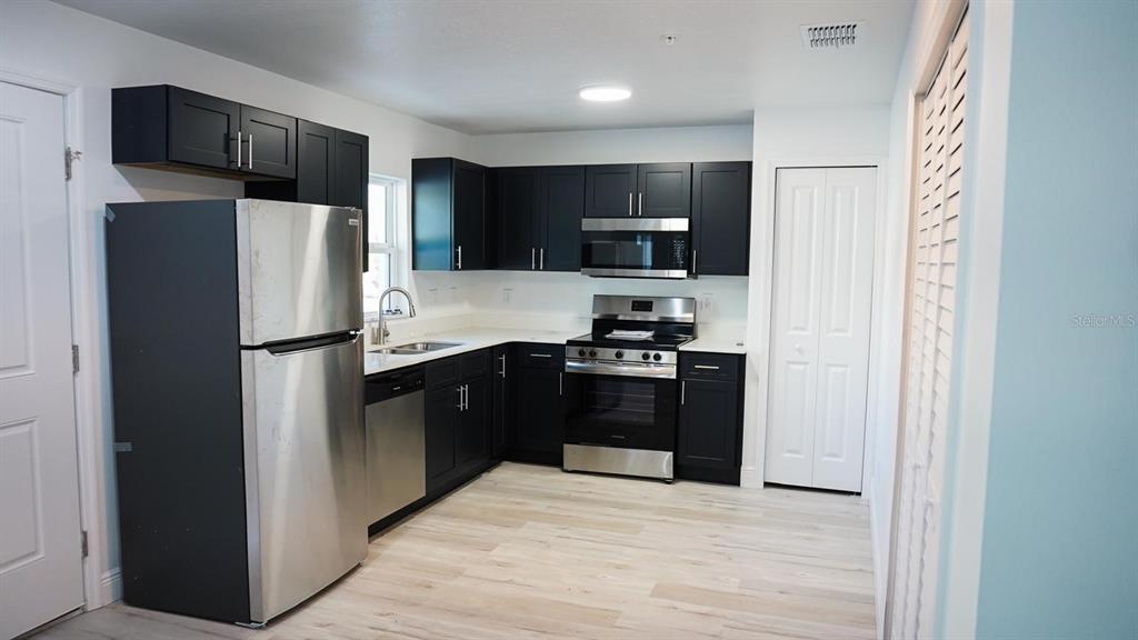 A kitchen features dark cabinets, stainless steel appliances, and a small dining table with chairs — 2201 CONWAY DRIVE UNIT 201, DELTONA, FL