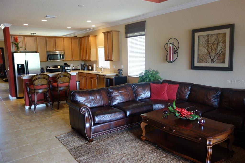 An open-concept kitchen and living room featuring a dark leather sectional and wooden cabinetry — 339 RIVER ENCLAVE COURT, BRADENTON, FL