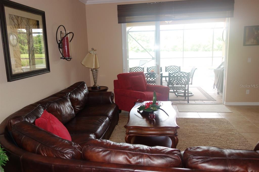A living room features a brown leather sectional, a red armchair, and a sliding glass door — 339 RIVER ENCLAVE COURT, BRADENTON, FL