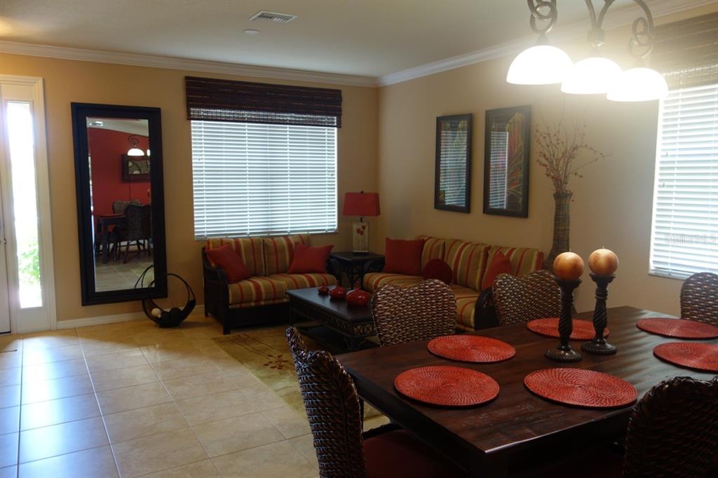 A dining area and living room with tile floors, striped sofas, and a wooden table — 339 RIVER ENCLAVE COURT, BRADENTON, FL