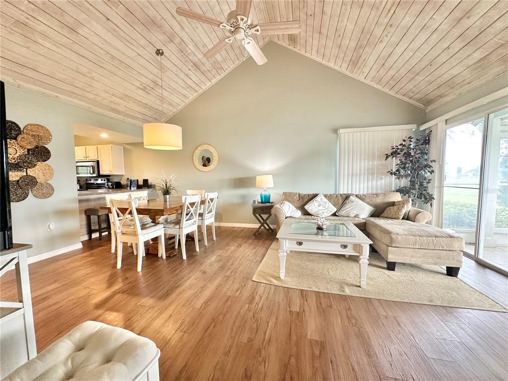 A living and dining area features vaulted wood-paneled ceilings, light flooring, and a sectional sofa — 1096 VILLA LANE UNIT 78, APOPKA, FL