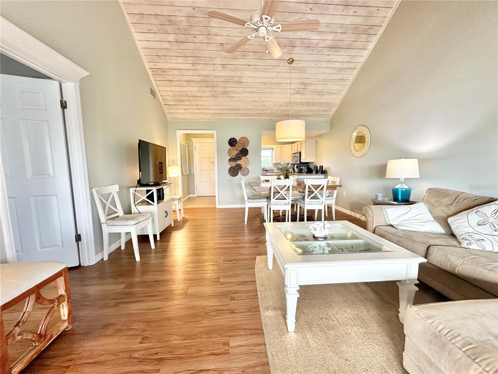 A living room and dining area feature wood-look flooring and a vaulted plank ceiling — 1096 VILLA LANE UNIT 78, APOPKA, FL