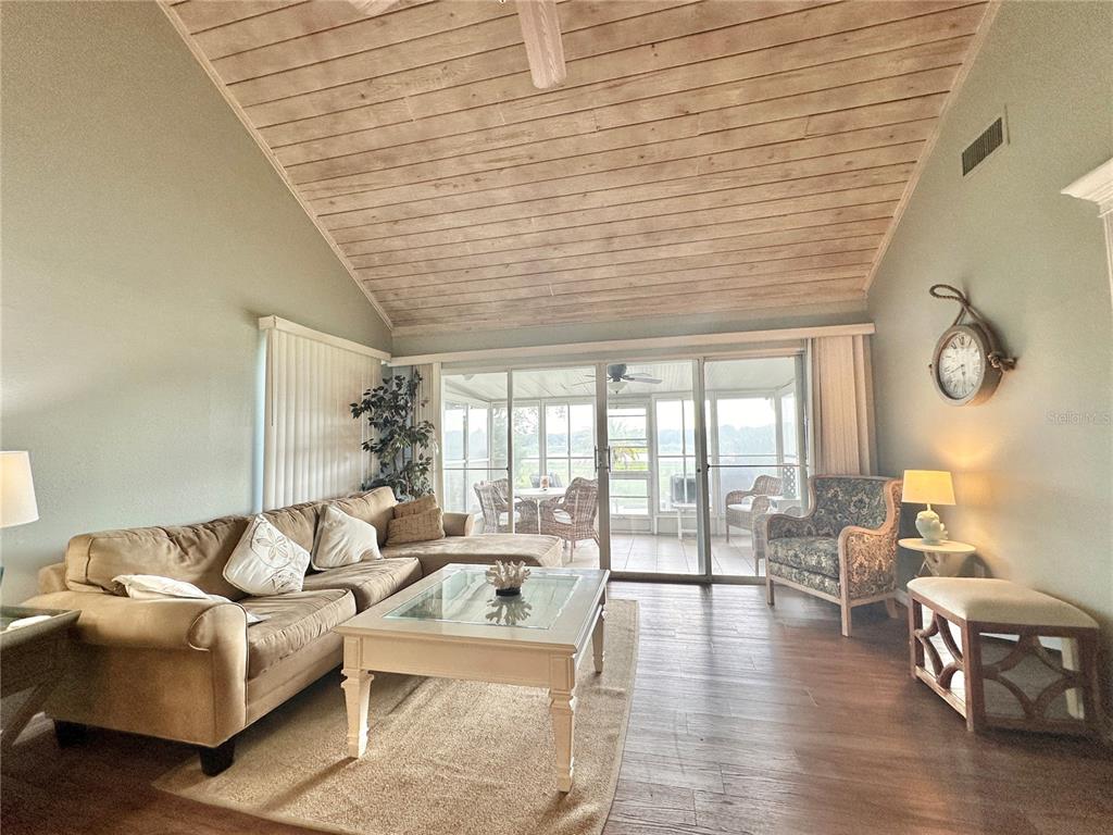 A living room features a vaulted wood-plank ceiling, wood flooring, and sliding glass patio doors — 1096 VILLA LANE UNIT 78, APOPKA, FL